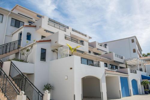 a white apartment building with stairs leading up to it at The Point Coolum in Coolum Beach