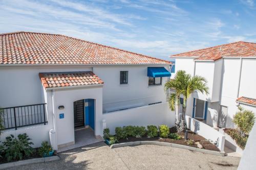 a white house with a blue door at The Point Coolum in Coolum Beach