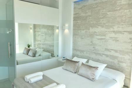 トレモリノスにあるLoft del Mar - Charming luxury apartment at La Rocaの白い部屋(ベッド1台、鏡付)