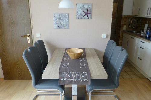 - une table à manger avec des chaises bleues et un bol dans l'établissement Villa Marina Wangerooge, à Wangerooge