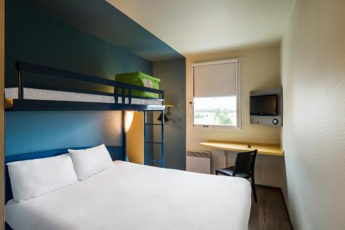 um quarto com uma cama, uma secretária e beliches em ibis budget Marne la Vallée Val d'Europe em Montévrain