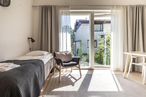 Un dormitorio con una cama y una silla y una ventana. en Spot Apartments Martinlaakso, en Vantaa