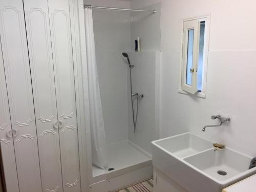 a white bathroom with a shower and a sink at La maison du lac in Auvers-sur-Oise