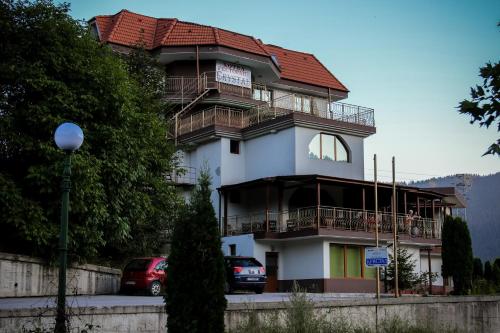 a tall white building with a red roof at Семеен хотел Кристал in Smolyan