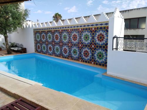 a swimming pool with a tile wall next to a house at Palais didi in Meknès