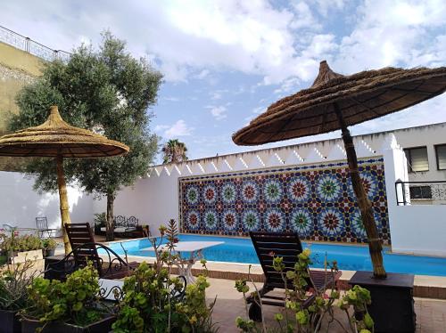 eine Terrasse mit Stühlen und Sonnenschirmen neben einem Pool in der Unterkunft Palais didi in Meknès