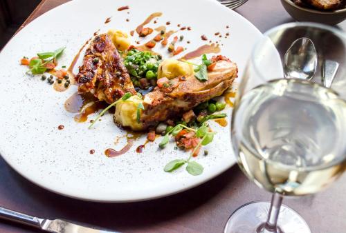 a white plate with food and a glass of wine at The Bonham in Edinburgh