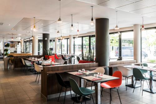 um restaurante com mesas, cadeiras e janelas em ibis budget Marne la Vallée Val d'Europe em Montévrain