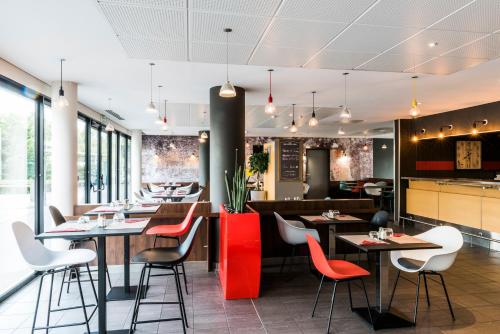 a restaurant with red and white chairs and tables at ibis budget Marne la Vallée Val d'Europe in Montévrain