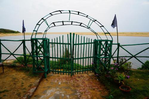 a green gate with flowers next to a body of water at Lotus an Eco Resort Konark in Konārka