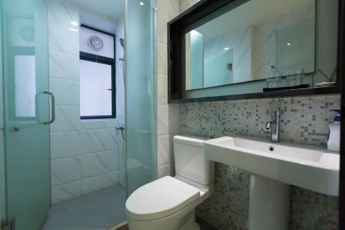 La salle de bains est pourvue de toilettes, d'un lavabo et d'une douche. dans l'établissement Po Si Zhineng Apartment, à Zhongshan