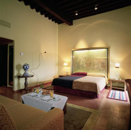 トルヒーリョにあるパラドール デ トルヒーリョのベッドルーム1室(壁に絵画が描かれたベッド1台付)