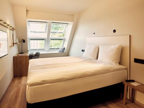 a bedroom with a large white bed with two windows at Schwabinger Wahrheit by Geisel in Munich