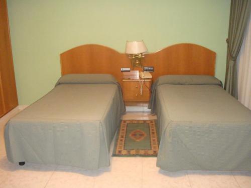 1 dormitorio con 2 camas, mesa y lámpara en Hostal Serpol, en Palencia