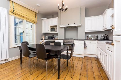 a kitchen with white cabinets and a black table and chairs at The River Cam Place - Enchanting 6BDR Home next to River Cam in Cambridge