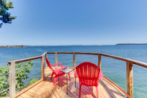 two red chairs and a table on a dock on the water at Olympus View Home in Port Ludlow
