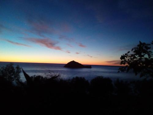 a sunset over the ocean with a small island in the water at Verde Mare in Alassio