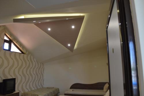 a room with a ceiling with a couch and a tv at Eos Hotel in Vidin