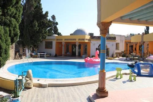 a large swimming pool with a house in the background at Ben's House in El Maamoura