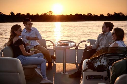 a group of people sitting on a boat on the water at Victoria Falls River Lodge in Victoria Falls