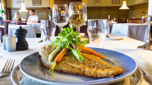 a plate of fish with carrots on a table with wine glasses at Hotel Kryb I Ly Kro in Taulov
