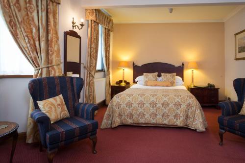 a bedroom with a bed and two chairs at Best Western Sysonby Knoll Hotel in Melton Mowbray