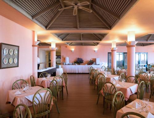 uma sala de jantar com mesas e cadeiras com paredes cor-de-rosa em Dom Pedro Garajau no Caniço