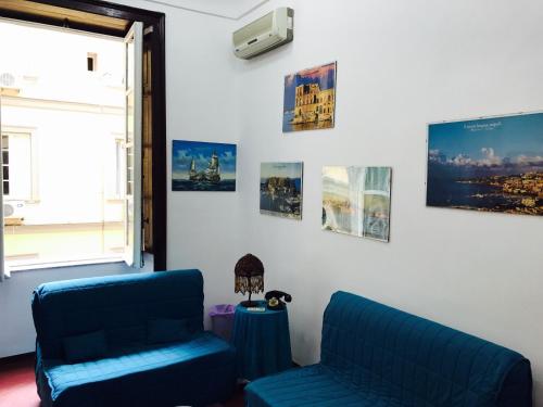 una sala de estar con 2 sillas azules y carteles en Parthenope's home, en Nápoles