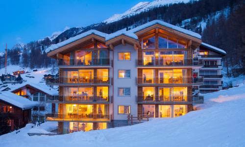 a large building with lights on in the snow at Matthiol Appartements in Zermatt
