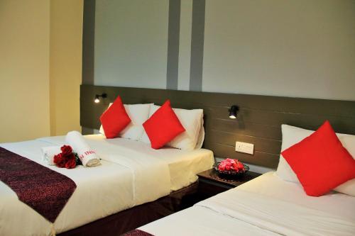 a hotel room with two beds with red pillows at Sun Inns Hotel Pasir Penambang (KS Botanic) in Kuala Selangor