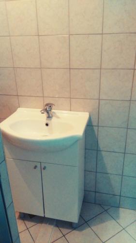 uma casa de banho com um lavatório branco e paredes em azulejo em Soba Centar em Banja Luka