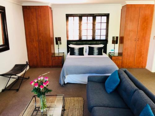 a bedroom with a bed and a blue couch at The Tarragon in Hout Bay
