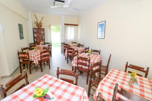 a restaurant with red and white tables and chairs at Hotel Karyatides in Agia Marina Aegina