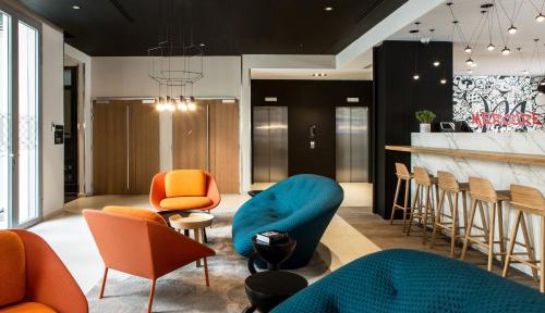 a lobby with orange and blue chairs and a bar at Mercure Paris 17 Batignolles in Paris