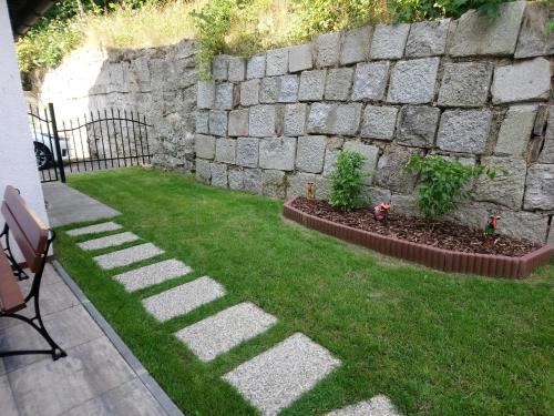 a garden with a stone wall and some grass at Penzion u Krtka in Kraslice