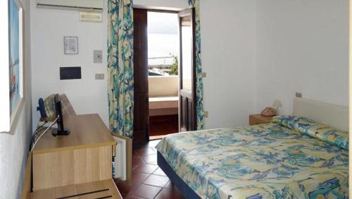 a bedroom with a bed and a desk with a telephone at Hotel Bellavista in Santa Marina Salina