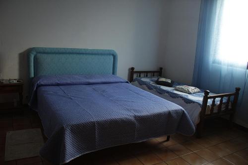 a small bedroom with a blue bed and a window at Casa vacanze Piscinas in Piscinas