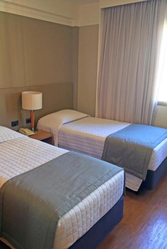 a hotel room with two beds and a lamp at Transamerica Executive Bela Cintra (Paulista) in Sao Paulo