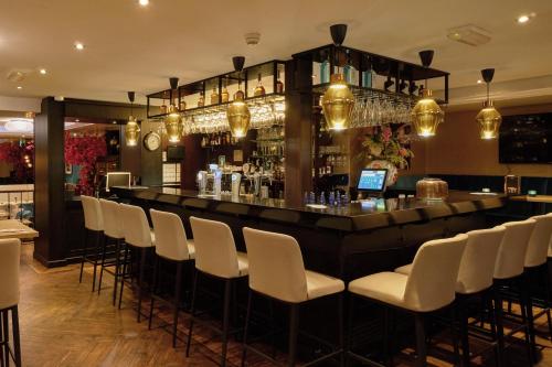 a bar in a restaurant with white chairs at Boutique Hotel Chariot - Amsterdam Schiphol Airport in Aalsmeer