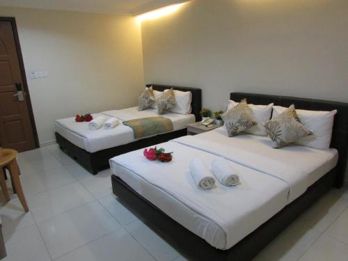 two beds in a hotel room with flowers on them at Safari Hotel in Kuala Lumpur