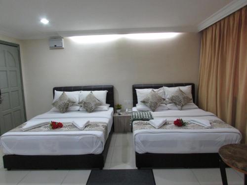 two beds in a hotel room with red flowers on them at Safari Hotel in Kuala Lumpur
