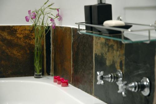 a bathroom sink with a vase with flowers in it at The Tarragon in Hout Bay