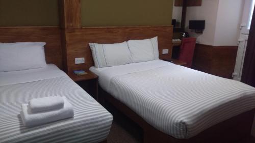 two beds in a hotel room with towels on them at Leith House in Edinburgh