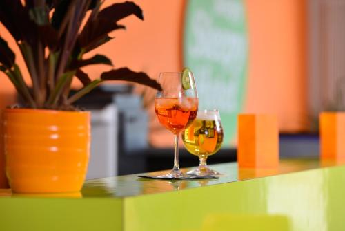 two wine glasses sitting on a table with a potted plant at SleepySleepy Hotel Dillingen in Dillingen an der Donau