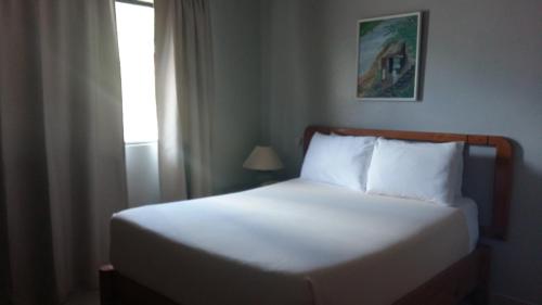 a bedroom with a white bed with a window at Hotel Zapata in Boca Chica
