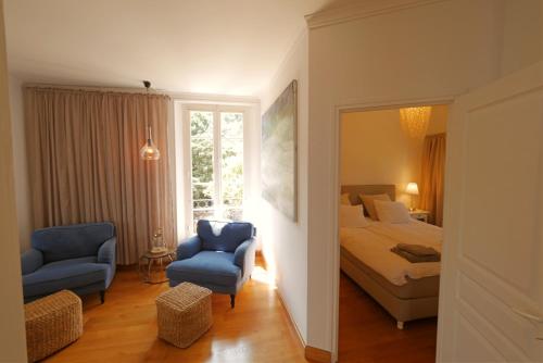 - une chambre avec un lit et deux chaises bleues dans l'établissement Villa Le Trayas Supérieur, à Espéro-Pax