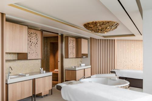 a bathroom with two beds and a tub and a sink at Royal Champagne Hotel & Spa in Champillon