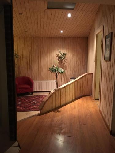 a hallway with a staircase in a room with a red chair at Hain Casa Hotel in Punta Arenas