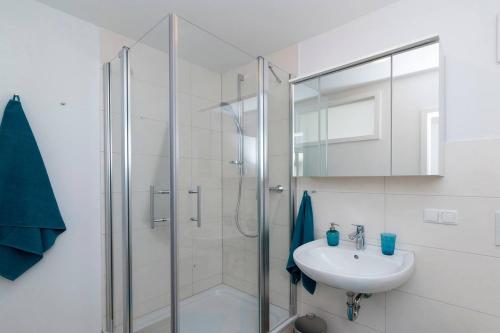 ein weißes Bad mit einer Dusche und einem Waschbecken in der Unterkunft Schönblick - gemütlich übernachten! in Ober-Hambach
