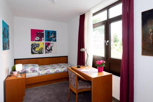 a bedroom with a desk and a bed and a window at Panoramablick Appartement - traumhaft! in Ober-Hambach